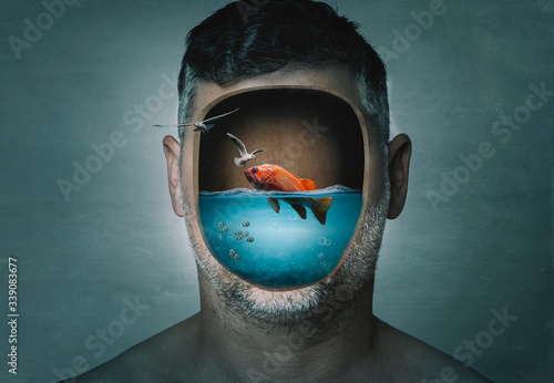 Surreal portrait of man with cropped face filled with water with a fish inside on a blue background. Surreal image. Surrealism. photo