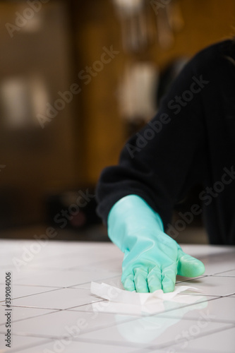Disinfecting surfaces from bacteria or Covid-19, hand with glove cleaning kitchen surface with disinfectant wet wipe.