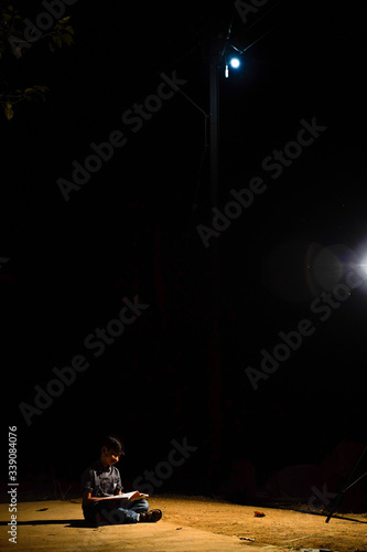 Fototapeta Naklejka Na Ścianę i Meble -  Poor child doing his homework in the street light