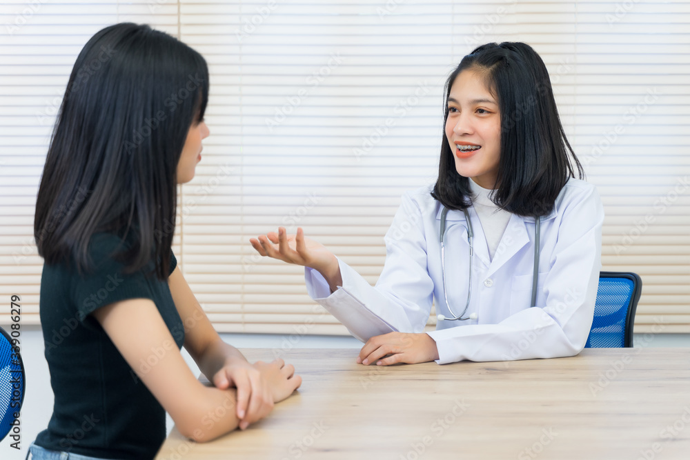 Young Asian female doctor gives consultation and listen to adult female patient’s symptoms in office. Patient having consultation with doctor in office. Medical and healthcare concept.