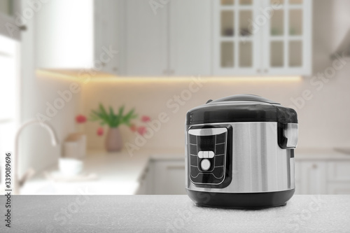 Modern electric multi cooker on table in kitchen. Space for design