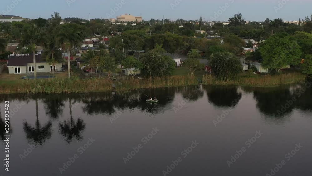 Aerial zoom in of two men fishing on a city park lake surrounded by palm trees, Southern Florida Aerial zoom in of two men fishing on a city park lake surrounded by palm trees, Southern Florida