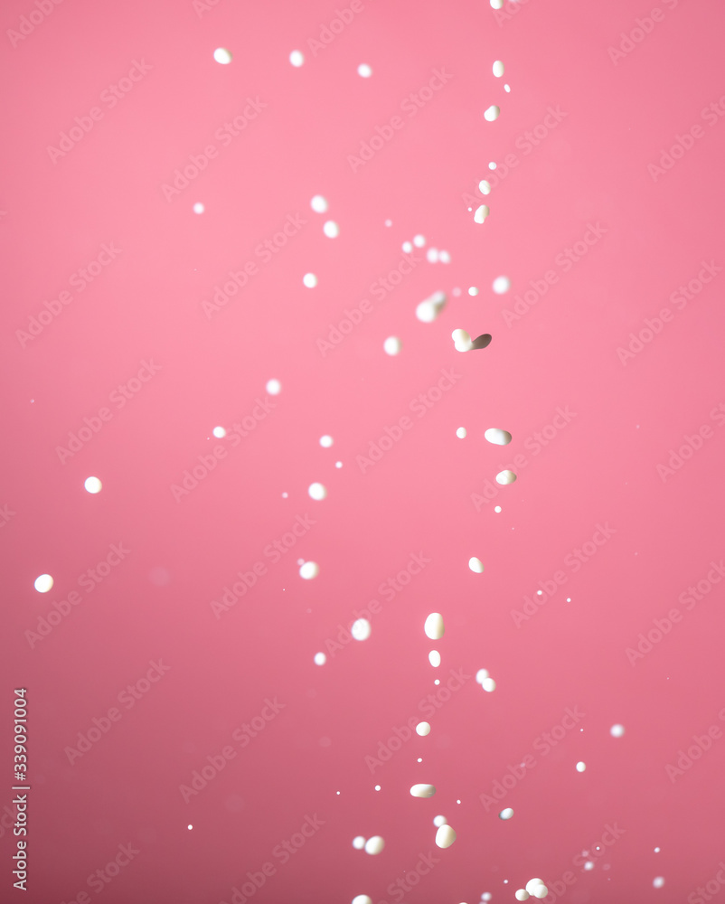 Splashing milk on a pink background.
