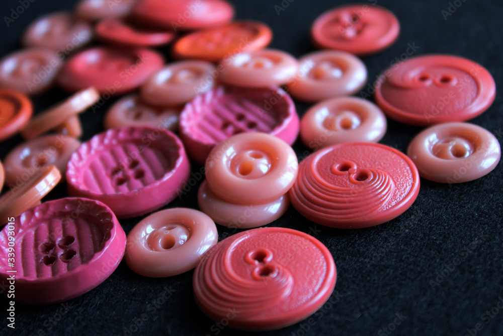 Pink buttons of different shapes. Hardware. Black background. Close-up. The inscription in Russian Pink buttons of different shapes. Hardware. Black background. Close-up. The inscription in Russian
