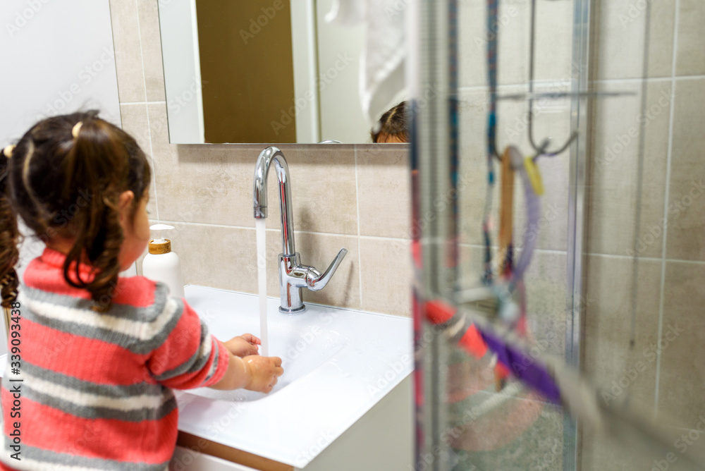Toddler child washing her hands in the sink. Clean hands protect against infection and virus. Selective focus. Toddler child washing her hands in the sink. Clean hands protect against infection and virus. Selective focus.