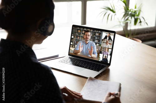 E-learning via virtual application, videocall video conferencing activity, colleagues working together concept. Pc screen view over woman shoulder, listen tutor gain new knowledge noting information