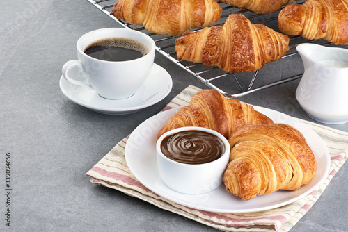 Croissants, chocolate butter, coffee and milk on a gray background.