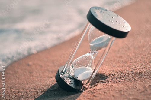 Hourglass at beach coast as time passing concept for business deadline, urgency and running out of time. © Evgeniy