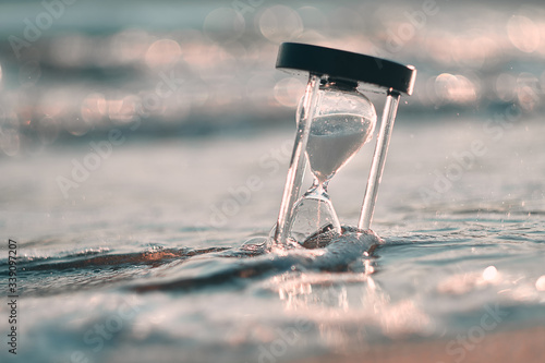 Hourglass at beach coast as time passing concept for business deadline, urgency and running out of time.