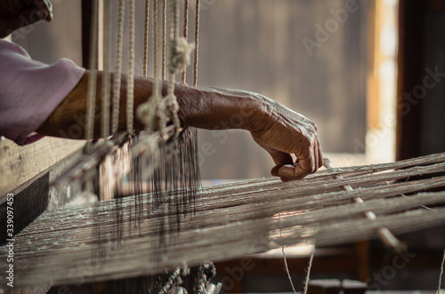 Old woman working with her hands on a rustical loom photo