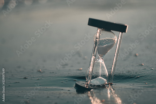 Hourglass at beach coast as time passing concept for business deadline, urgency and running out of time.