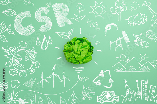 Creative idea and Innovation of environmental, Corporate Social Responsibility (CSR), eco-friendly business concept with crumpled green paper light bulb and environmental sketch on green background photo