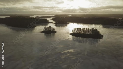 Smooth wet ice at frozen lake with islands during sunset in Finland. Aerial shot. photo