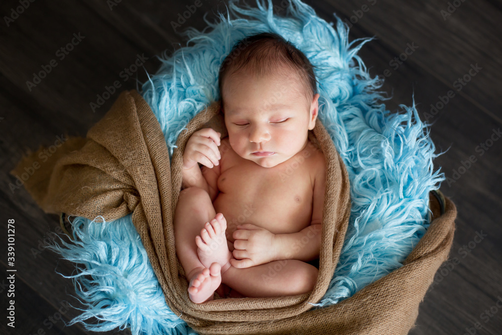 Cute little newborn baby boy, sleeping in basket with wrap Cute little newborn baby boy, sleeping in basket with wrap