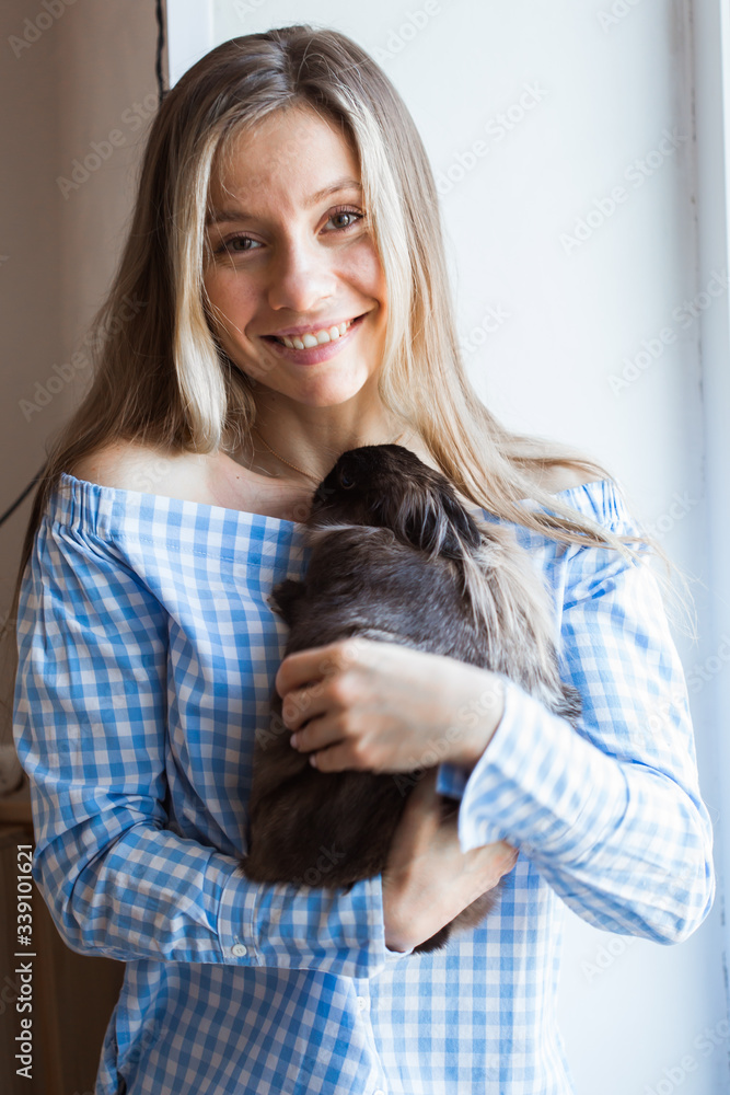 Pet and Easter concept - Happy girl hugging brown rabbit at home.