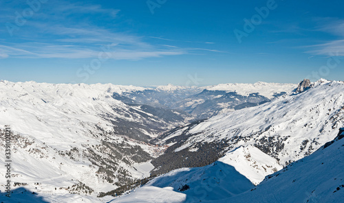Panoramic view down snow covered valley in alpine mountain range with conifer pine trees © Paul Vinten
