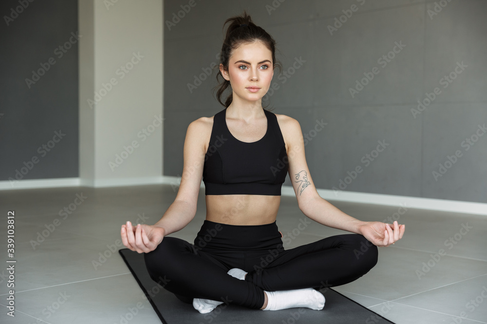 Photo of focused young woman meditating while sitting with legs crossed Photo of focused young woman meditating while sitting with legs crossed