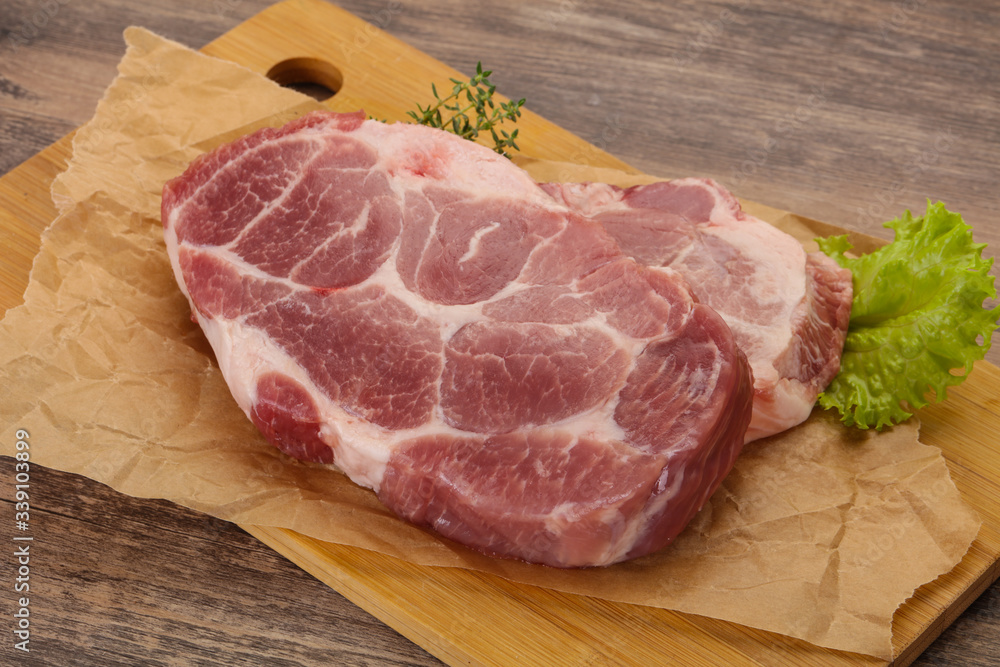 Raw pork steak over wooden board