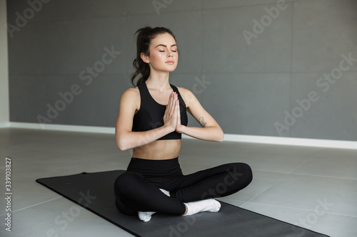 Photo of focused young woman meditating and holding palms together