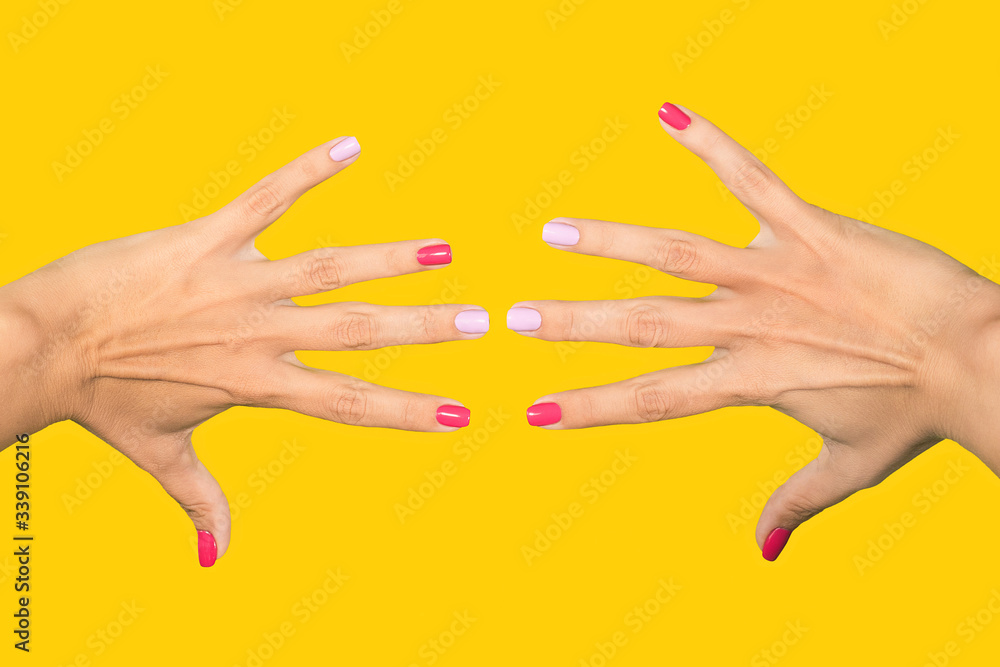 Closeup view photography of two beautiful female hands with trendy modern bright asymmetric nail design perfect for bright sunny summer days wear.