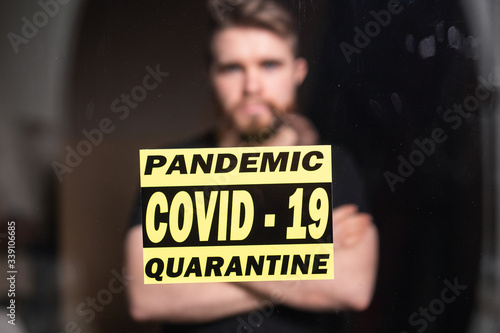 Coronavirus, quarantine, covid-19 and pandemic concept. Sad and sick man of corona virus looking through the window. Stay at home.