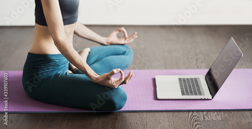 Young woman practicing yoga at home, online video training, Girl doing exercises and meditate, Yoga, balance, meditation, relaxation, healthy lifestyle, online training class concept