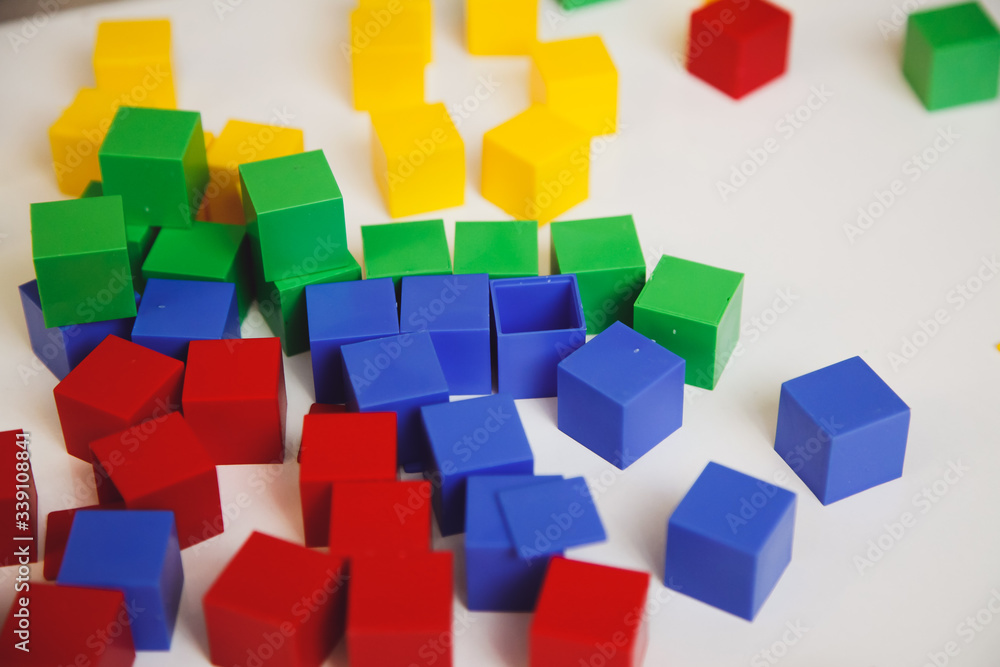 Child's hands with colorful cubes on the white table. Child playing at the table. Early development of a child concept. Child's hands with colorful cubes on the white table. Child playing at the table. Early development of a child concept.