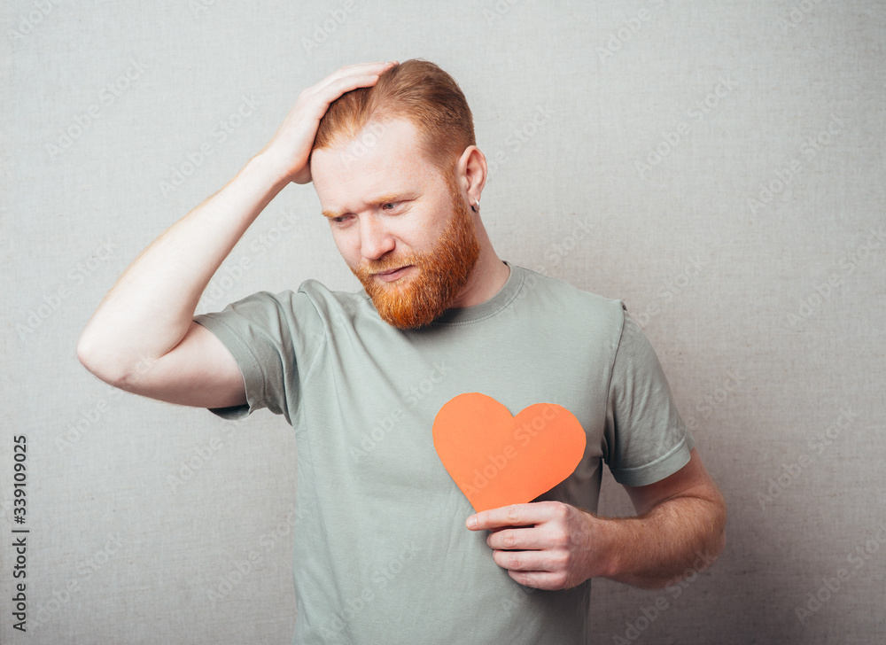 bearded man sad and holding a heart in his hands