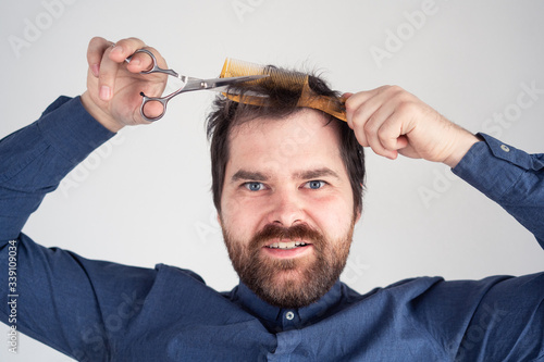 man with a comb and scissors in his hands cuts his hair