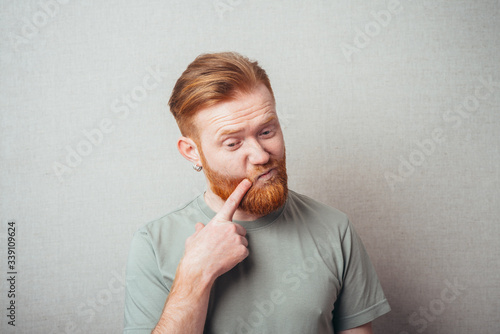 bearded man put his finger to his cheek photo