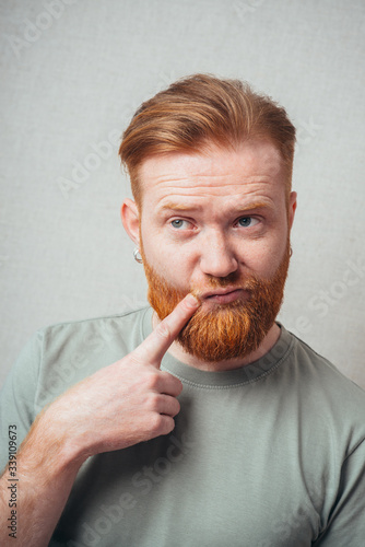 bearded man put his finger to his cheek photo