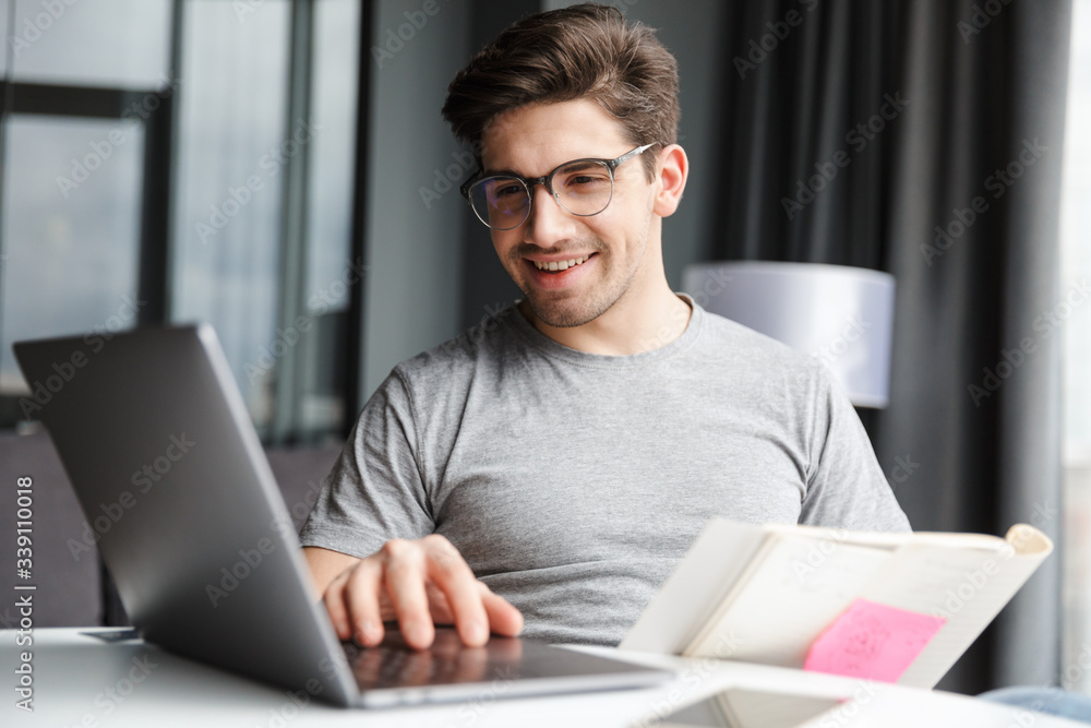 Optimistic young man using laptop computer Optimistic young man using laptop computer