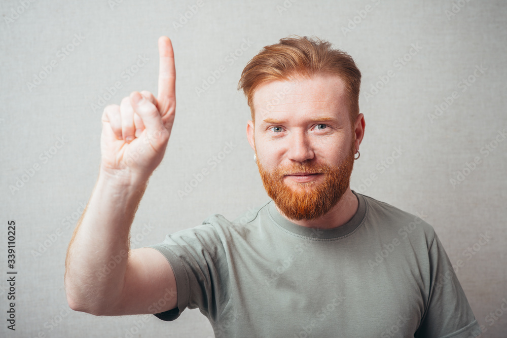 portrait of a bearded man shows his index finger up portrait of a bearded man shows his index finger up