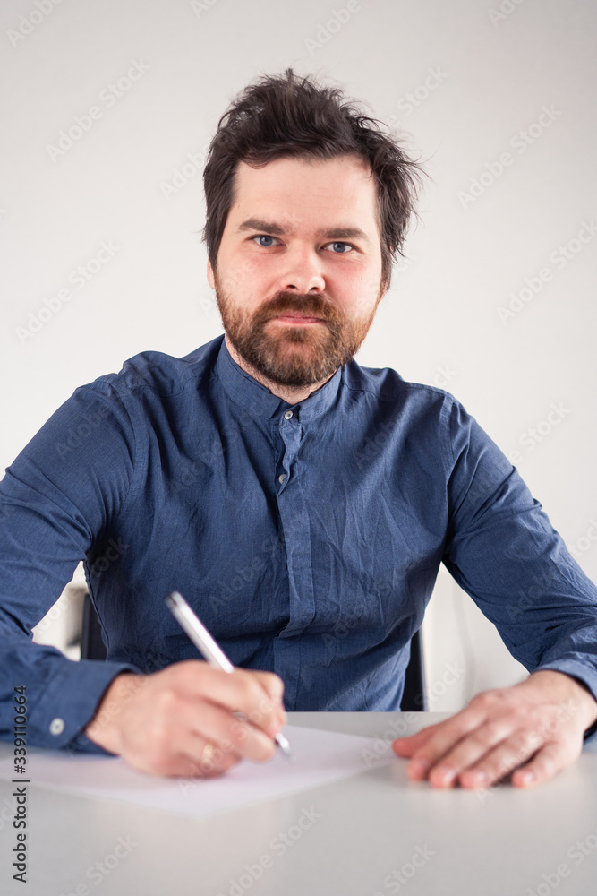 man writes on a piece of paper at the table