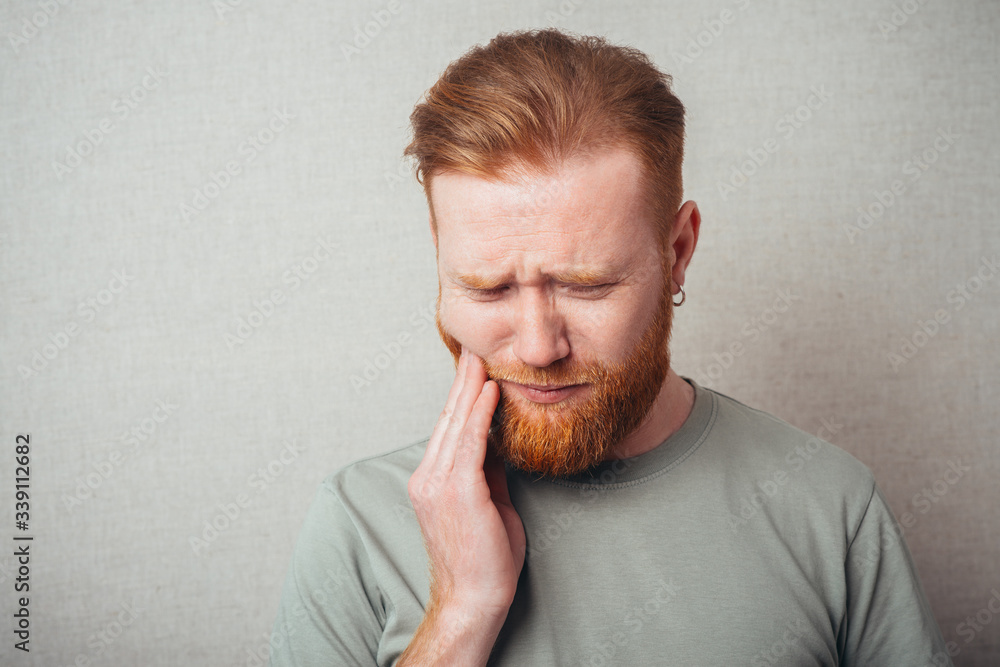 a young man with a beard in shirt feels toothache a young man with a beard in shirt feels toothache