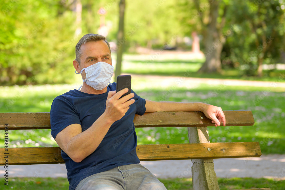 Man wearing a face mask sitting using a mobile Man wearing a face mask sitting using a mobile