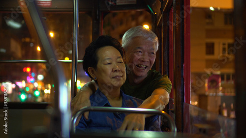 Photography Asian elder couple have fun travel through Hong Kong city tram at night light