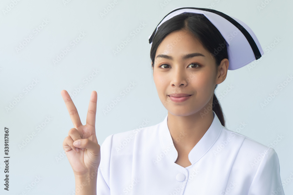 portrait of serious asian woman nurse isolated pointing 2 fingers up; confident and professional female nurse or medical worker pointing two fingers up, two points or v for victory portrait of serious asian woman nurse isolated pointing 2 fingers up; confident and professional female nurse or medical worker pointing two fingers up, two points or v for victory