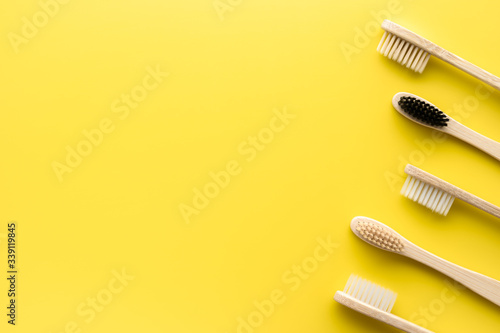 Zero waste concept. Set of eco friendly bamboo toothbrushes on a bright yellow background. Flat lay  copy space  horizontal orientation. Layout natural organic hygiene products.