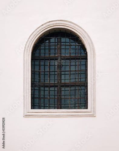 Antique old window with iron bars framed on a gray wall. The Jesuit Church in Lviv.