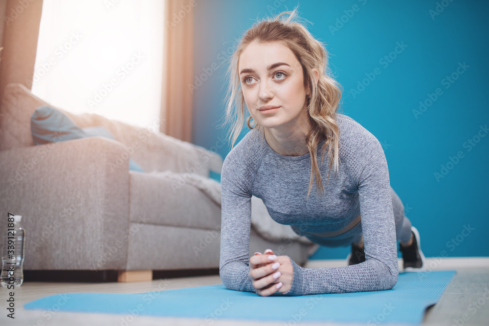 Beautiful lady with blond hair in activewear doing planking exercise on yoga mat at ow apartment. Concept of motivation and healthy lifestyle. Beautiful lady with blond hair in activewear doing planking exercise on yoga mat at ow apartment. Concept of motivation and healthy lifestyle.