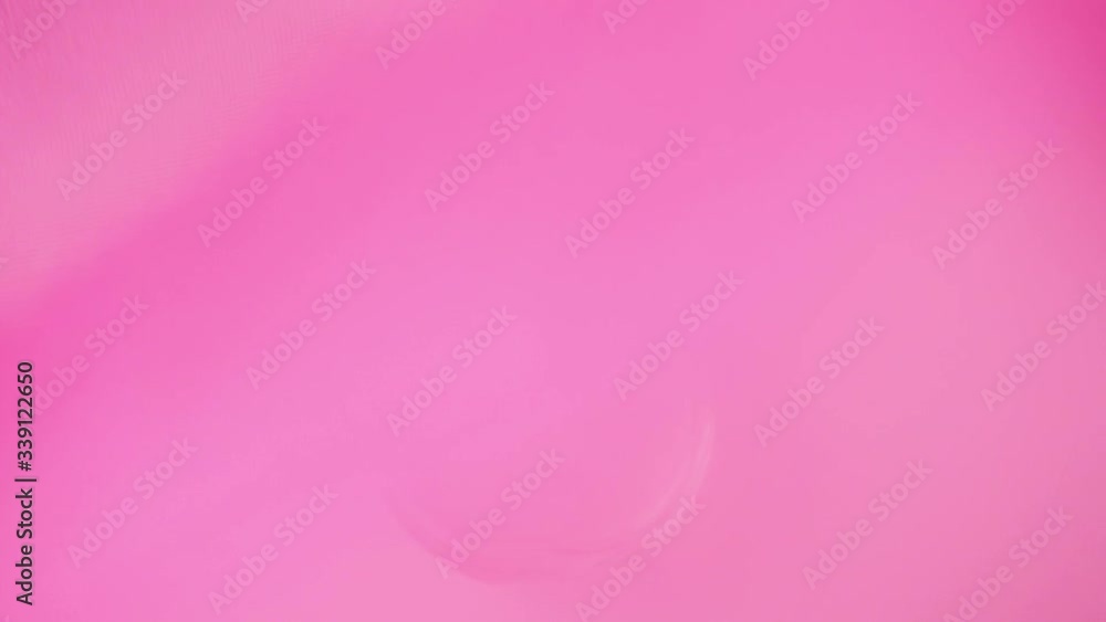 Oval surfaced bottle with pink perfumes or essential oils is on the white table under a pink fabric. Pink fabric waves, abruptly flutters away from the table exposing perfumes. Close up. Slow motion Oval surfaced bottle with pink perfumes or essential oils is on the white table under a pink fabric. Pink fabric waves, abruptly flutters away from the table exposing perfumes. Close up. Slow motion