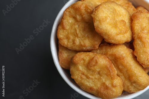 Bucket with tasty chicken nuggets on black table, top view