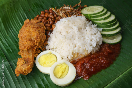 Nasi Lemak-Malaysian cuisine. A fragrant rice dish cooked in coconut milk and pandan leaf commonly found in Malaysia. Served with sambal, anchovies, peanut and cucumber.