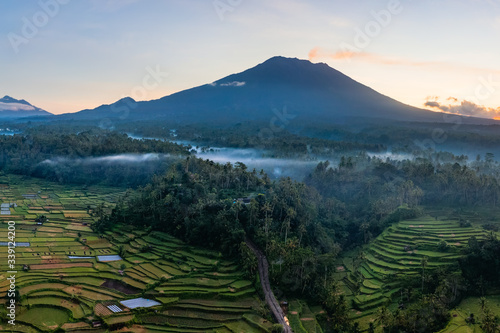 Volcano with smoke plume and rice fields at sunrise, Bali