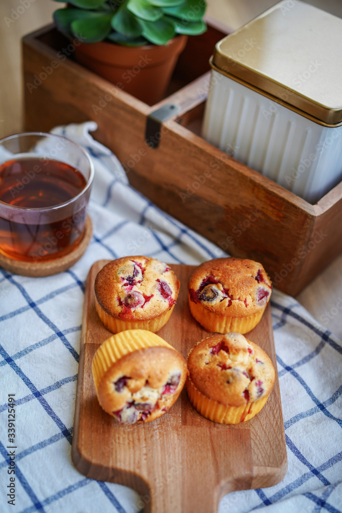 Muffins with cranberries and chocolate are beautifully laid out on the cutting Board, around the atmosphere of home and comfort, beautiful interior, natural wood, a Cup of tea