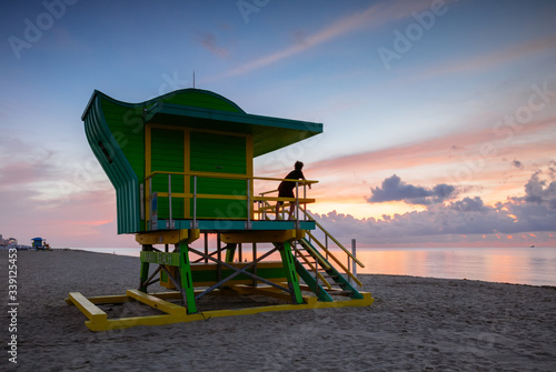 Young man on lifeguard cabin at sunrise, Miami beach, USA