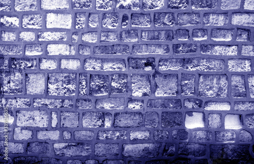 Wall made of old stones in blue tone.
