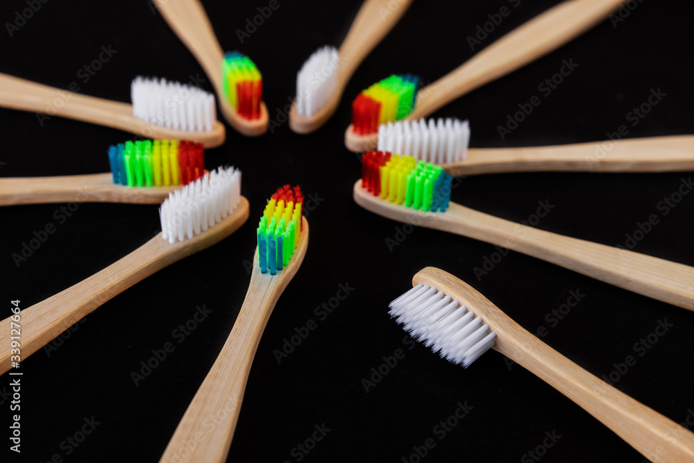 Group of white and rainbow eco bamboo toothbrushes, on black background. Top view. Natural organic product for oral hygiene. Dental zero waste and no plastic concept. Safe for the earth. Group of white and rainbow eco bamboo toothbrushes, on black background. Top view. Natural organic product for oral hygiene. Dental zero waste and no plastic concept. Safe for the earth.