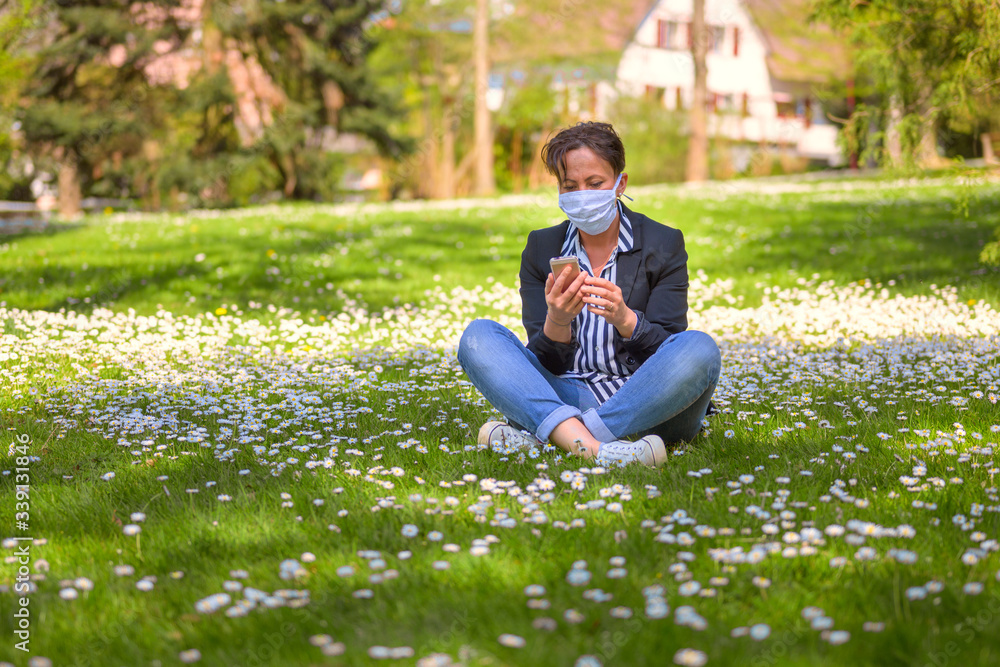 Woman sitting in the grass wearing a face mask Woman sitting in the grass wearing a face mask